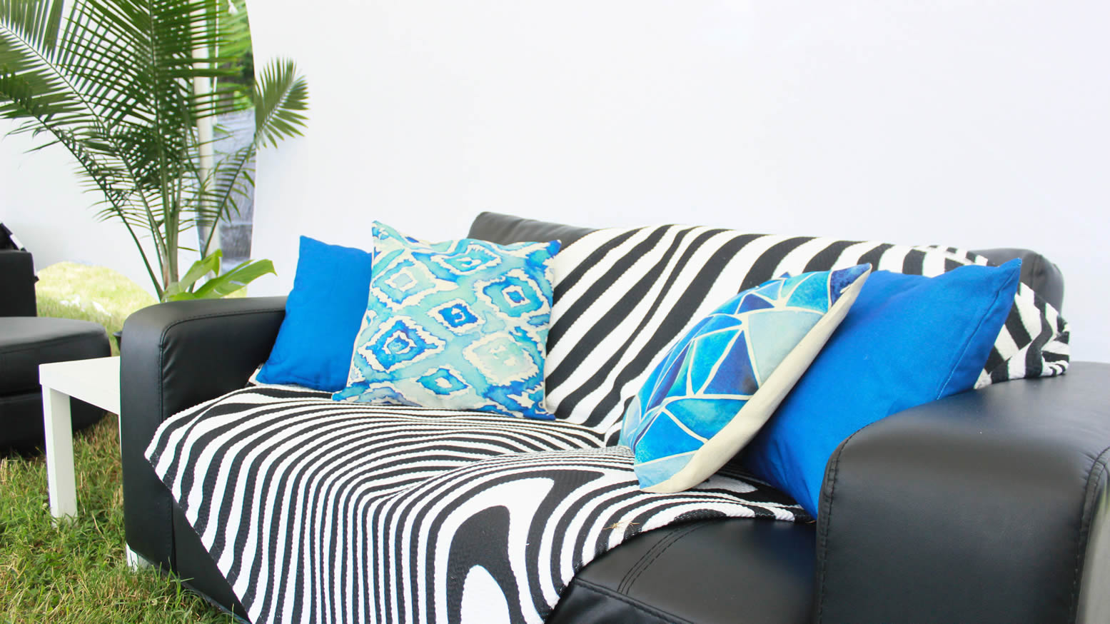 a black lounge chair with a checkerboard throw blanket and blue pillows eccessories by ellen www.eccessoriesbyellen.com