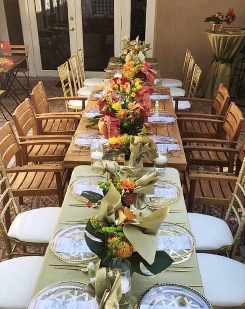 wood tables and chairs outside with cream table cloth and tropical floral arrangements eccessories by Ellen www.eccessoriesbyellen.com